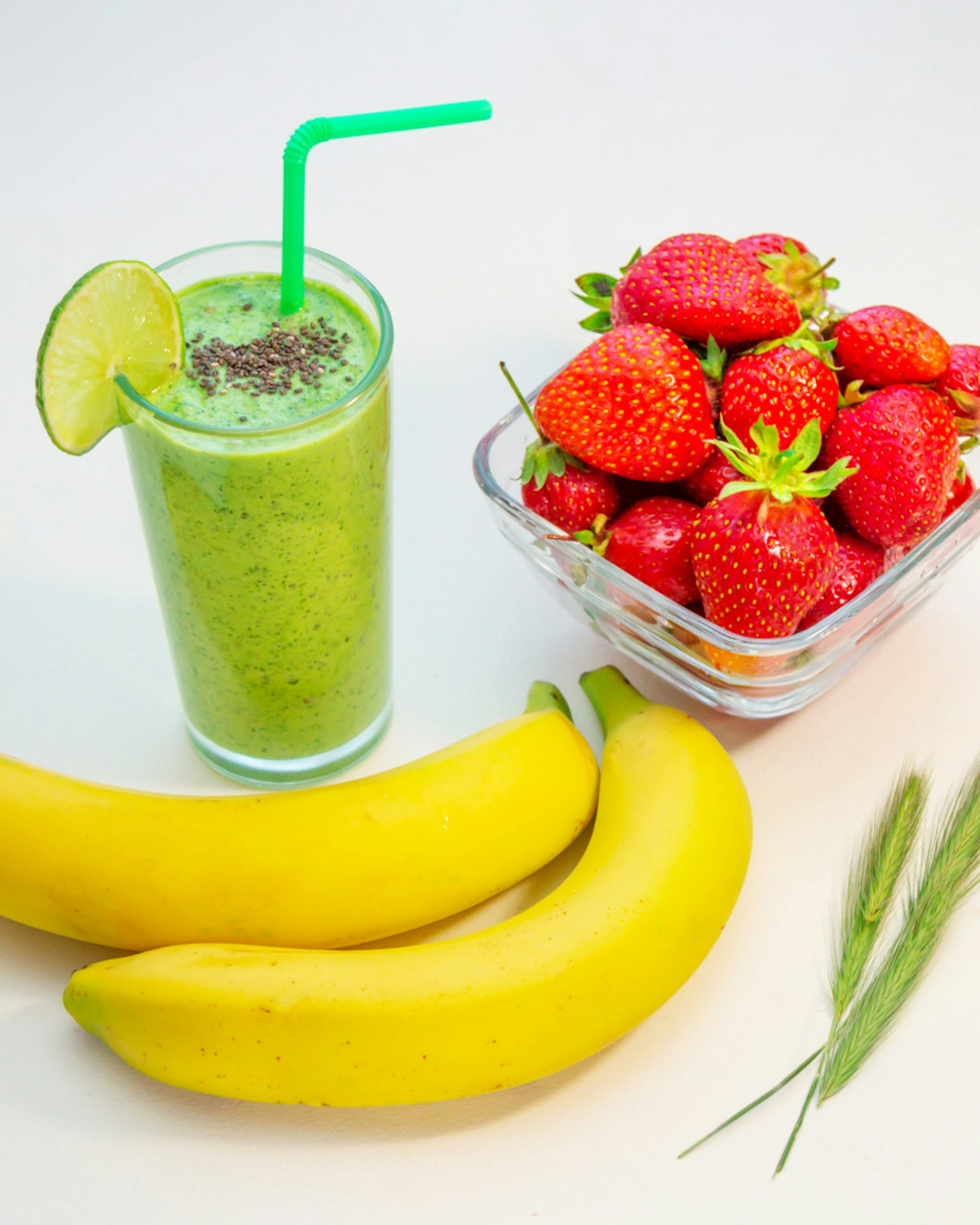 Grüner Smoothie im Glas Bananen und reife Erdbeeren auf dem Tisch. Gesundes Frühstück.