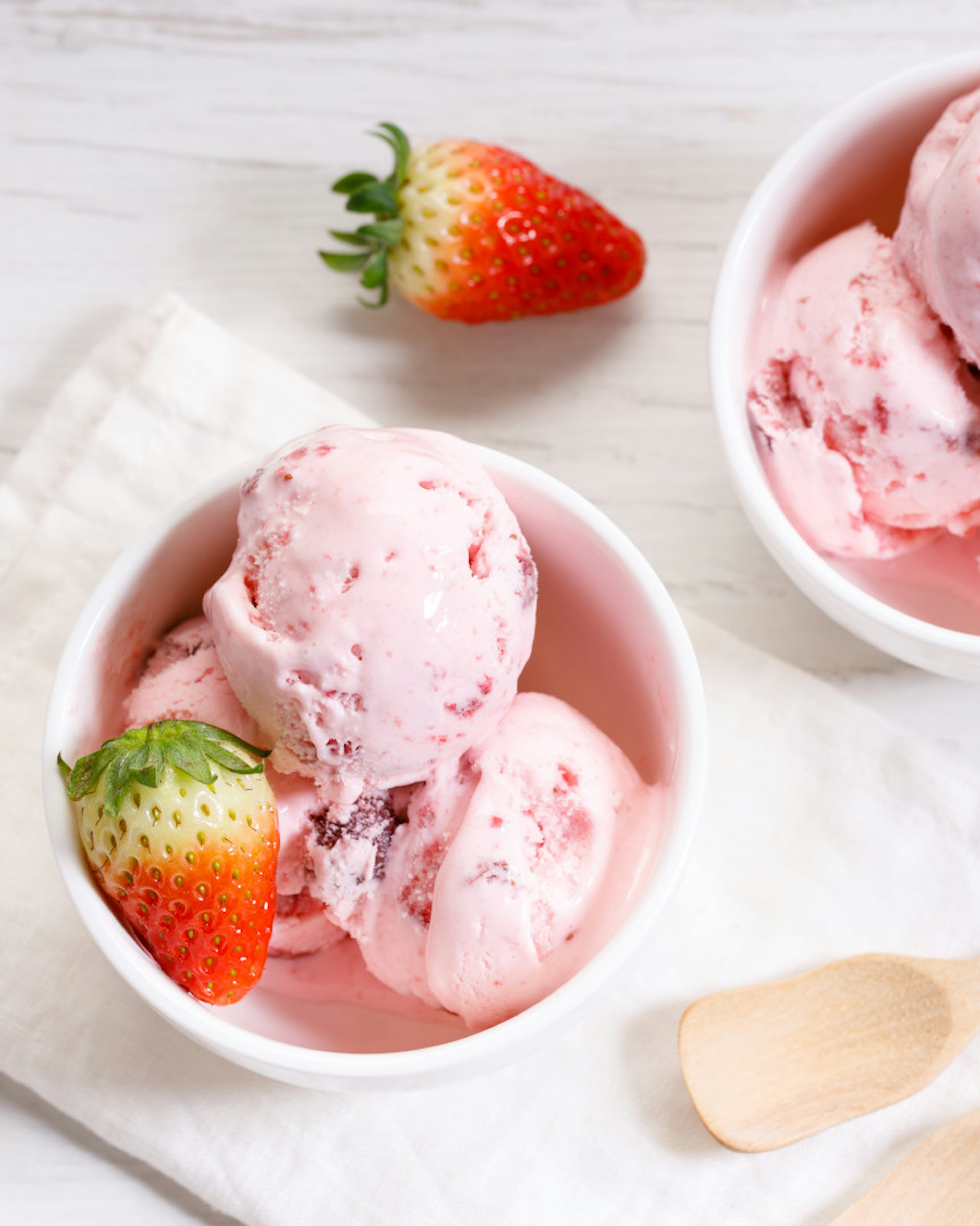 Erdbeer-Eiskugeln in weißer Schüssel mit frischen Erdbeeren