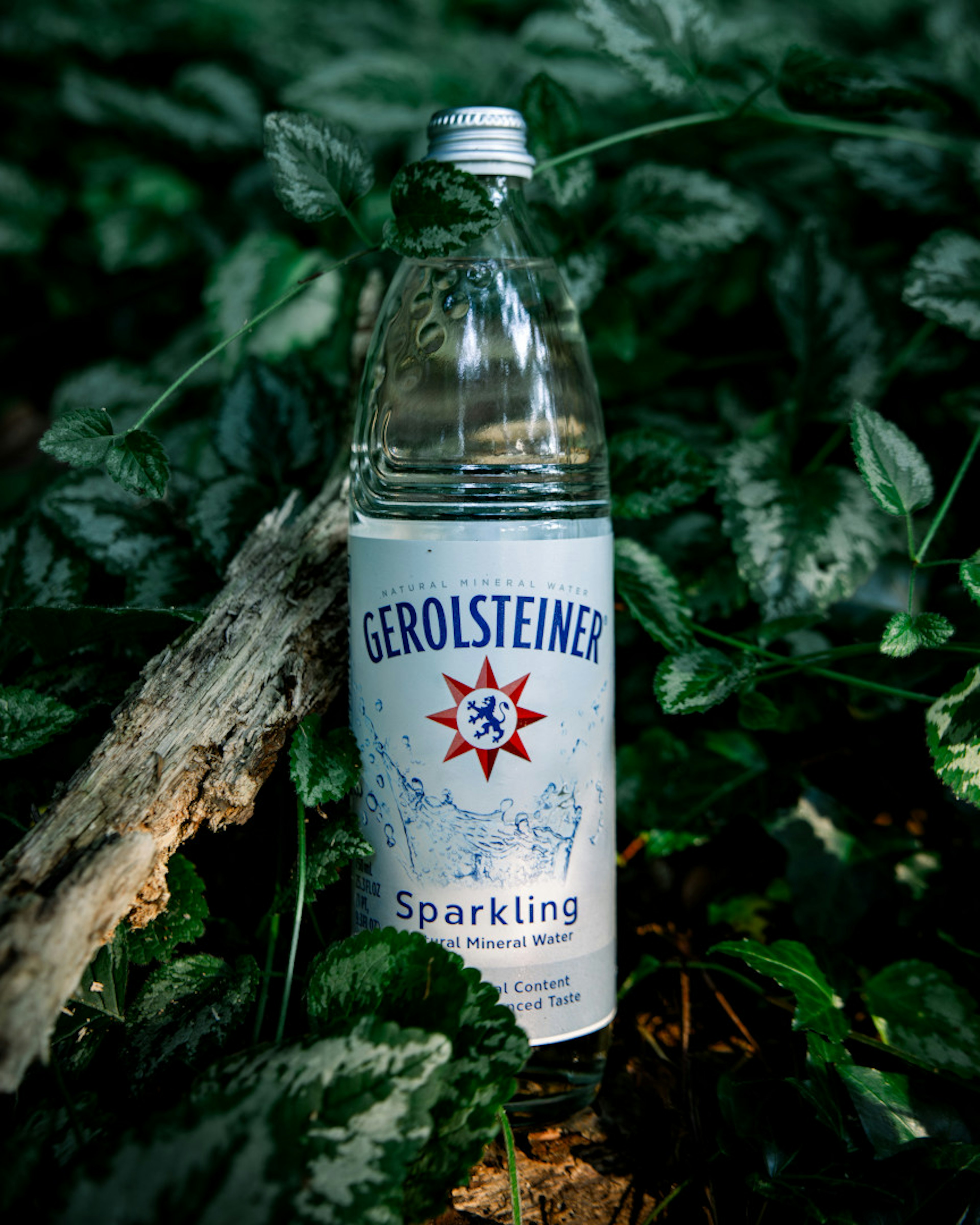 Gerolsteiner bottle surrounded by green plants outdoors. 